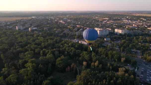 Veduta aerea drone di mongolfiere colorate che sorvolano il parco verde e il distretto industriale nella piccola città europea al tramonto estivo — Video Stock