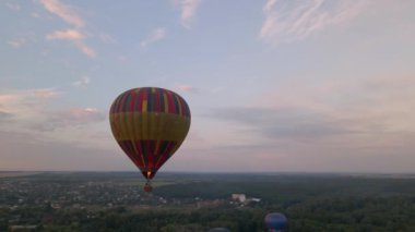 Yeşil park üzerinde uçan renkli sıcak hava balonları ve yaz gündoğumunda küçük Avrupa kentindeki binalar, hava manzarası