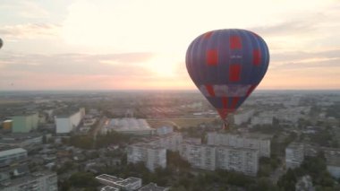Yeşil park üzerinde uçan renkli sıcak hava balonları ve yaz gündoğumunda küçük Avrupa kentindeki binalar, hava manzarası