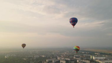 Yaz günbatımında küçük Avrupa kentindeki binaların üzerinde uçan renkli sıcak hava balonları, hava manzarası