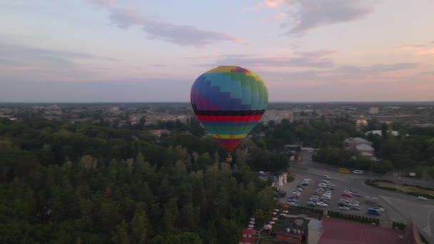 Bunte Heißluftballons fliegen bei Sommersonnenaufgang über grünen Park in kleiner europäischer Stadt, Luftaufnahme — Stockvideo