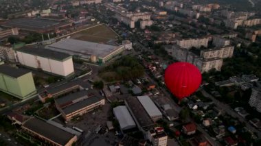 Sıcak hava balonu, yaz günbatımında Avrupa 'nın küçük bir şehrinde, sanayi bölgesinde binaların üzerinde uçuyor.