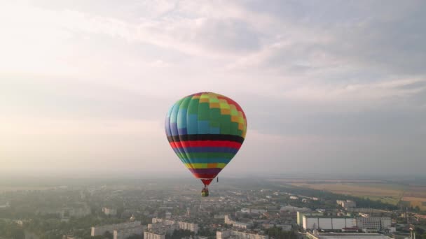Kleurrijke hete lucht ballonnen vliegen over gebouwen in kleine Europese stad bij zonsondergang, luchtfoto 's — Stockvideo
