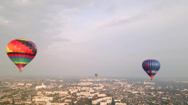 Kleurrijke hete lucht ballonnen vliegen over gebouwen in kleine Europese stad bij zonsondergang, luchtfoto 's — Stockvideo