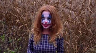 Sarı yapraklarla poz veren Joker makyajlı kızıl saçlı kadın.