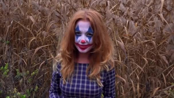 Redhead γυναίκα με Joker make-up για το Halloween ποζάρουν σε κίτρινο φόντο φύλλα — Αρχείο Βίντεο