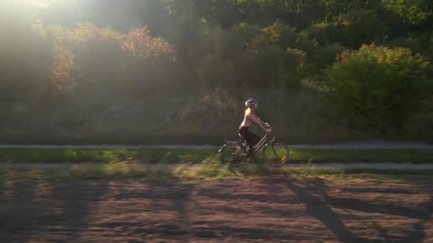 Aerial slow motion shot młodej kobiety sportu jeździ rowerem po wiejskiej drodze w letni zachód słońca. Zdrowy styl życia rowerzystów — Wideo stockowe