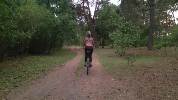 Tiro aéreo de mulher do esporte jovem monta bicicleta na estrada da floresta na noite de verão. Estilo de vida de ciclismo saudável — Vídeo de Stock