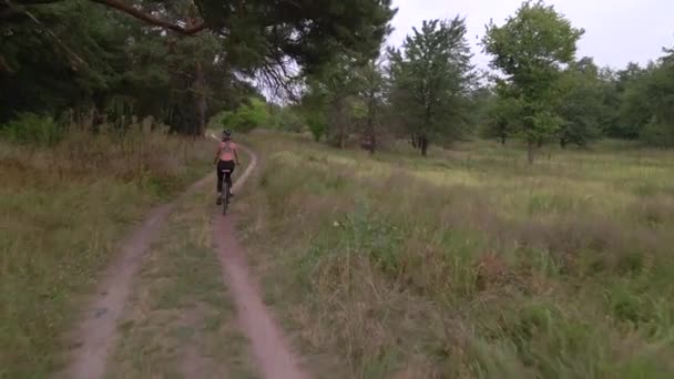 Luchtfoto van jonge sporter fietst 's zomers op bosweg. Gezonde fietsstijl — Stockvideo