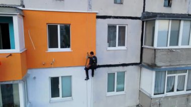 Boyama ve dekorasyon binaları. Yüksek bir binanın şantiyesinde çalışan bir işçi. Yüksek irtifa mühendisliği tasarımı için tehlikeli bir iş. Demir ve beton.