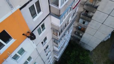 Boyama ve dekorasyon binaları. Yüksek bir binanın şantiyesinde çalışan bir işçi. Yüksek irtifa mühendisliği tasarımı için tehlikeli bir iş. Demir ve beton.