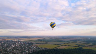 Ukrayna 'nın Kiev bölgesinde yaz gündoğumunda küçük Avrupa şehrinde yeşil parkın üzerinde uçan renkli sıcak hava balonlarının insansız hava aracı görüntüsü