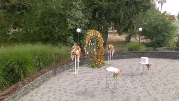 Luchtfoto bruiloft ceremonie met boog versierd met herfstbladeren en bloemen, witte stoelen voor de gasten, buiten — Stockvideo