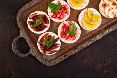 Pirinç crispbread ve metal tepsi kahverengi zemin üzerine taze meyve ile snack. Sağlıklı gıda kavramı. Yat, görünümü, yuvarlak top. Gevrek ekmek ile sağlıklı snack. Kolay meze tarifi.