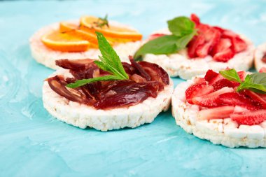 Pirinç crispbread ve mavi zemin üzerine taze meyve ile snack. Sağlıklı gıda kavramı. Yat, görünümü, yuvarlak top. Gevrek ekmek ile sağlıklı snack. Kolay meze tarifi.