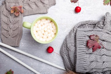 Gri örgü eldiven, atkı, şapka ve iğneler etrafında gri arka plan üzerinde hatmi ile kahve. Üstten görünüm. Uzay kopyalayın. Örgü iplik. Düz yatıyordu