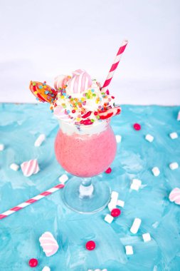 Berry, rasberry, çilek, çikolata şekerleme, lolipop mavi zemin üzerine pembe aşırı milkshake... Deli freakshake. Uzay kopyalayın. Gıda trend Overshake