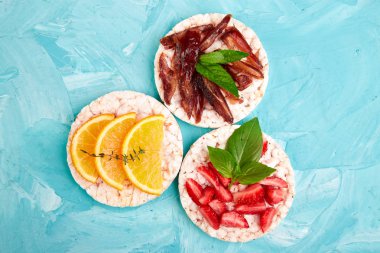 Pirinç crispbread ve mavi zemin üzerine taze meyve ile snack. Sağlıklı gıda kavramı. Yat, görünümü, yuvarlak top. Gevrek ekmek ile sağlıklı snack. Kolay meze tarifi.