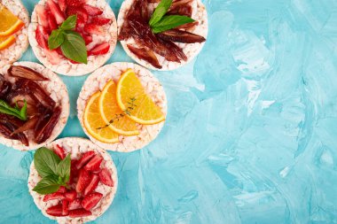 Pirinç crispbread ve mavi zemin üzerine taze meyve ile snack. Sağlıklı gıda kavramı. Yat, görünümü, yuvarlak top. Gevrek ekmek ile sağlıklı snack. Kolay meze tarifi.