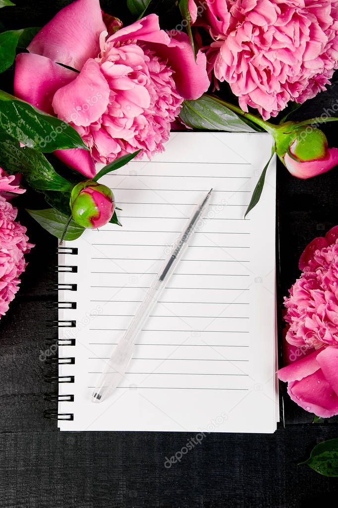 Beautiful pink peony flowers on black background with note or diary. Planing to do list. Copy space Top view. Flat lay. Empty blank.