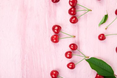 Olgun kiraz çilek ve vişne pembe bir arka plan üzerinde renkli parlak desen yaprak. Üstten görünüm. Düz yatıyordu. 