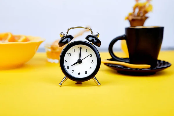 早咖啡 燕麦早餐与水果近黑色闹钟 花瓶花黄色背景 — 图库照片