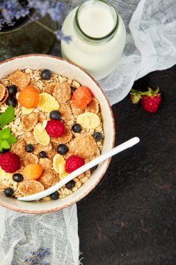 Sağlıklı vejetaryen kahvaltı. Yulaf ezmesi, granola ahududu ve yaban mersini kase üzerinde kahverengi zemin, buket lavanta ile. Üstten görünüm. Düz yatıyordu. 