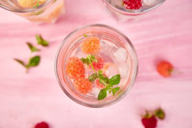 Aromalı su üç rengiyle ahududu - infused detoks kırmızı, turuncu, pembe bir arka plan üzerinde sarı... Yaz ev yapımı kokteyl serinletici. Üstten görünüm