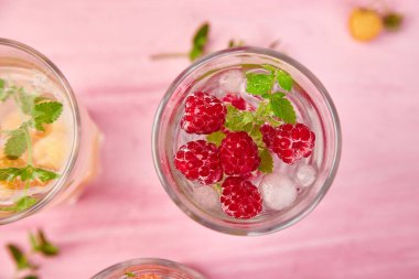 Aromalı su üç rengiyle ahududu - infused detoks kırmızı, turuncu, pembe bir arka plan üzerinde sarı... Yaz ev yapımı kokteyl serinletici. Üstten görünüm