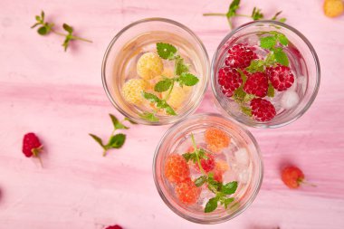 Aromalı su üç rengiyle ahududu - infused detoks kırmızı, turuncu, pembe bir arka plan üzerinde sarı... Yaz ev yapımı kokteyl serinletici. Üstten görünüm