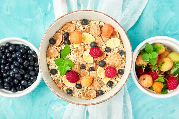 Healthy vegetarian breakfast. Oatmeal, granola with raspberries and blueberry in bowl over blue background, Bouquet lavender. Top view. Flat lay.