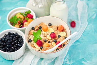 Sağlıklı vejetaryen kahvaltı. Yulaf ezmesi, granola ahududu ve yaban mersini kase üzerinde mavi arka plan, buket lavanta ile. Üstten görünüm. Düz yatıyordu. 