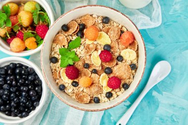 Sağlıklı vejetaryen kahvaltı. Yulaf ezmesi, granola ahududu ve yaban mersini kase üzerinde mavi arka plan, buket lavanta ile. Üstten görünüm. Düz yatıyordu. 