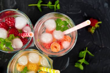 Aromalı su üç rengiyle ahududu - infused detoks kırmızı, turuncu, siyah zemin üzerine sarı... Yaz ev yapımı kokteyl serinletici. Üstten görünüm