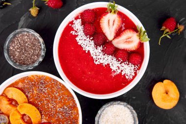 Güler yüzlü kase. Siyah arka plan üzerinde sağlıklı kahvaltı kase. Blackberry ve chia tohum ile kayısı güler yüzlü. Çilek ve Hindistan cevizi ile ahududu güler yüzlü. Vegan gıda. Üstten görünüm. Düz yatıyordu