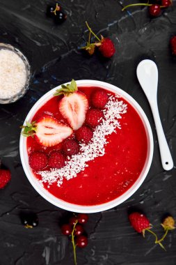 Güler yüzlü kase. Siyah arka plan üzerinde sağlıklı kahvaltı kase. Çilek ve Hindistan cevizi ile ahududu güler yüzlü. Vegan gıda. Üstten görünüm. Düz yatıyordu