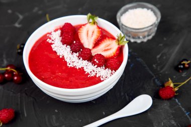 Güler yüzlü kase. Siyah arka plan üzerinde sağlıklı kahvaltı kase. Çilek ve Hindistan cevizi ile ahududu güler yüzlü. Vegan gıda