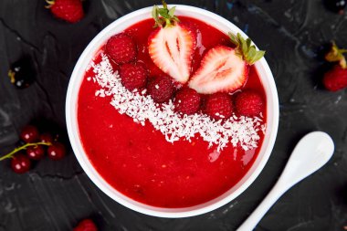 Güler yüzlü kase. Siyah arka plan üzerinde sağlıklı kahvaltı kase. Çilek ve Hindistan cevizi ile ahududu güler yüzlü. Vegan gıda. Üstten görünüm. Düz yatıyordu