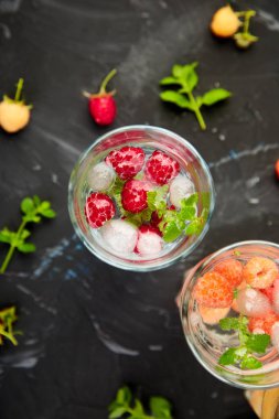 Aromalı su üç rengiyle ahududu - infused detoks kırmızı, turuncu, siyah zemin üzerine sarı... Yaz ev yapımı kokteyl serinletici. Üstten görünüm