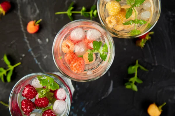 Aromalı su üç rengiyle ahududu - infused detoks kırmızı, turuncu, siyah zemin üzerine sarı... Yaz ev yapımı kokteyl serinletici. Üstten görünüm