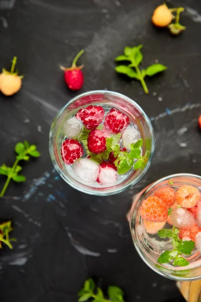 Aromalı su üç rengiyle ahududu - infused detoks kırmızı, turuncu, siyah zemin üzerine sarı... Yaz ev yapımı kokteyl serinletici. Üstten görünüm