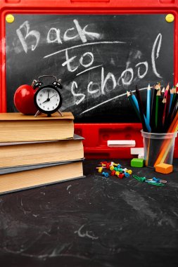 Blackboard tebeşir ile kitap, kalem, kırmızı elma yakınındaki kara tahta arka plan ile yazı okuluna geri dön