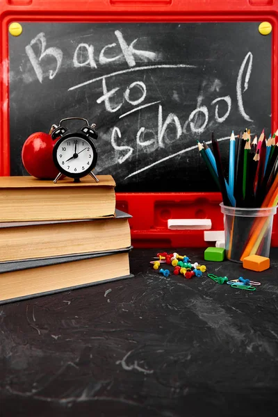 Blackboard tebeşir ile kitap, kalem, kırmızı elma yakınındaki kara tahta arka plan ile yazı okuluna geri dön