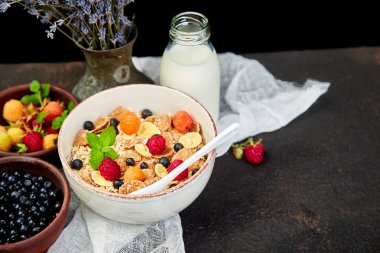 Sağlıklı vejetaryen kahvaltı. Yulaf ezmesi, granola ahududu ve yaban mersini kase üzerinde kahverengi zemin, buket lavanta ile. Üstten görünüm. Düz yatıyordu. 