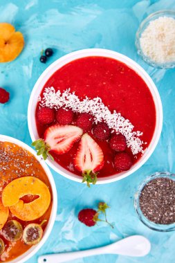 Güler yüzlü kase. Mavi arka plan üzerinde sağlıklı kahvaltı kase. Blackberry ve chia tohum ile kayısı güler yüzlü. Çilek ve Hindistan cevizi ile ahududu güler yüzlü. Vegan gıda. Düz yatıyordu. Üstten görünüm.