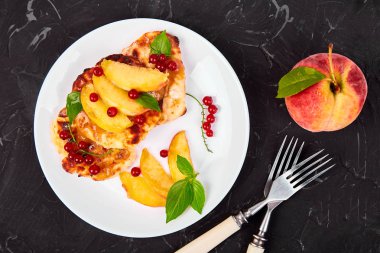 Süzme peynir krep, şeftali ile syrniki ve beyaz tabak siyah arka plan üzerinde meyveleri. Börek Lor. Üstten görünüm. Düz yatıyordu