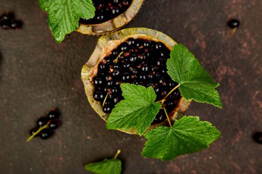 Blackcurrant meyveler yaprakları, siyah frenk üzümü yeşil kase ile. Üstten görünüm. Uzay kopyalayın. Düz yatıyordu.