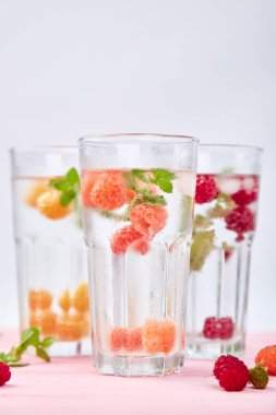 Aromalı su üç rengiyle ahududu - infused detoks kırmızı, turuncu, pembe bir arka plan üzerinde sarı... Canlandırıcı yaz ev yapımı cocktai