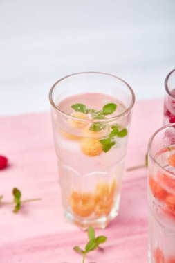 Detox infused flavored water with three color raspberry - red, orange, yellow on pink background.. Refreshing summer homemade cocktai clipart