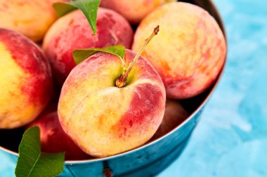 Olgun şeftali bir kapta, sepet mavi masada. Uzay kopyalayın. Düz yatıyordu. Üstten görünüm. 